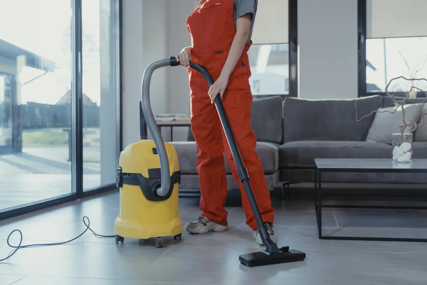 Professional cleaner vacuuming a bright living room